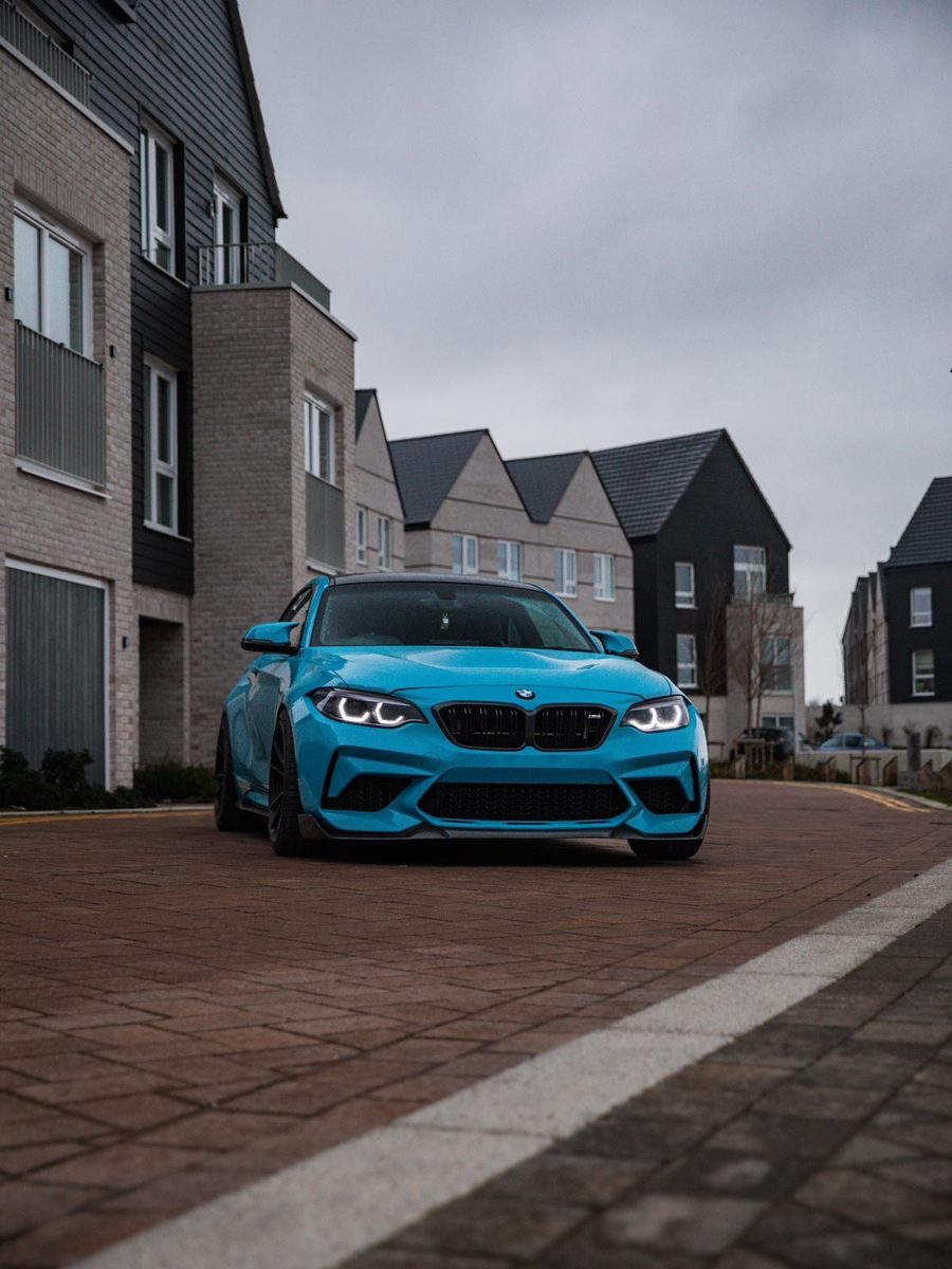 The M2 with its headlights on in a quiet street at dusk